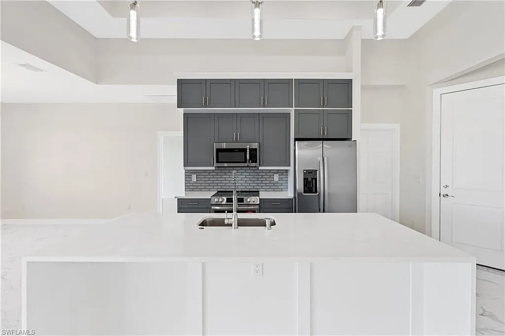 Kitchen with dark cabinetry and a white waterfall island