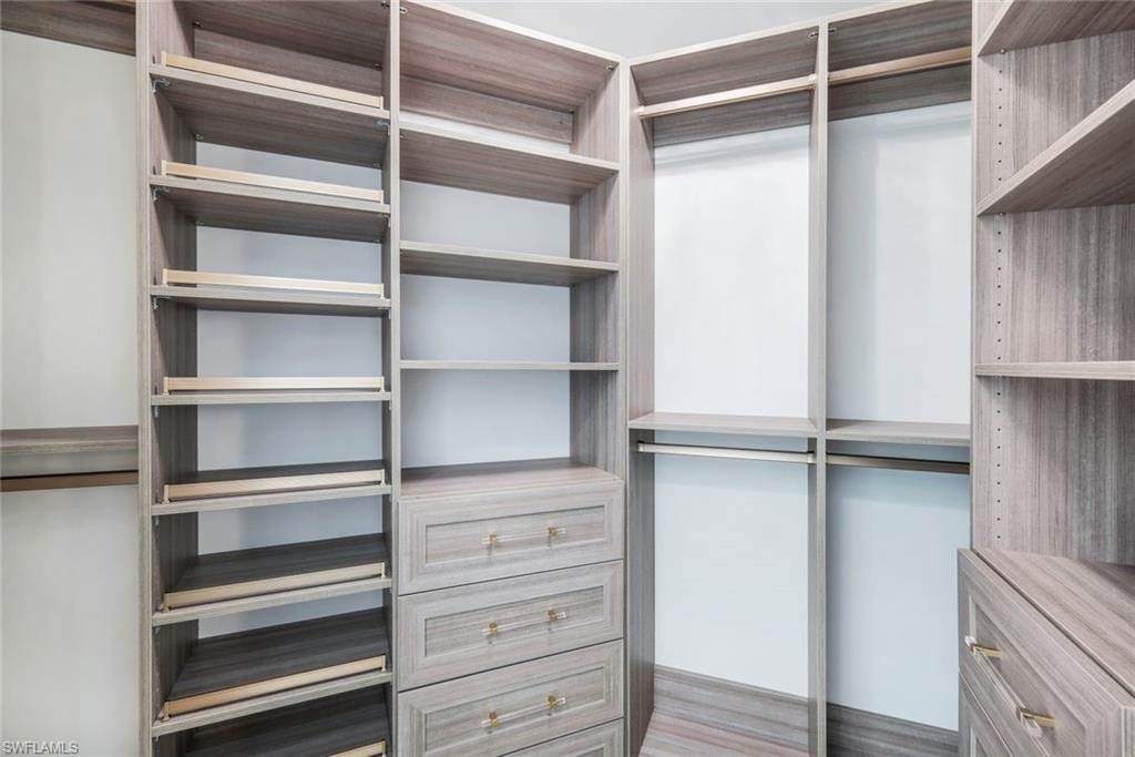 Custom walk-in closet with woodgrain shelving, drawers and hanging storage